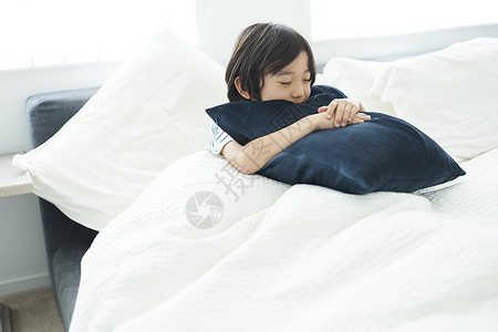 在床上抱着抱枕的男孩图片