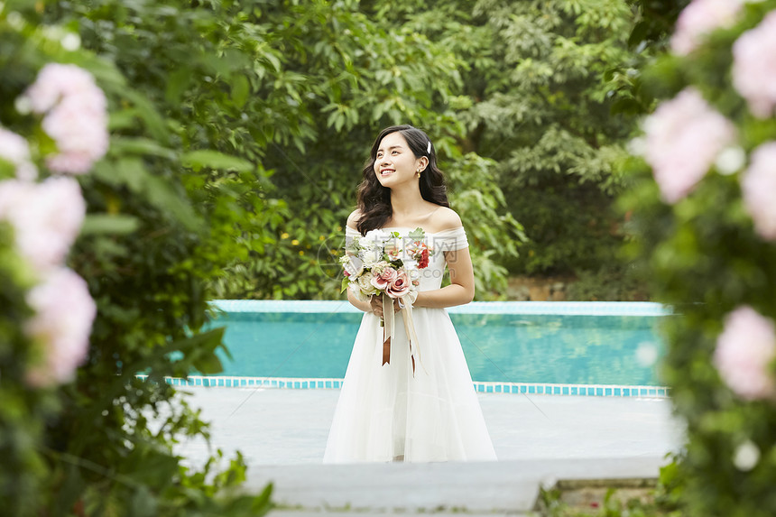 泳池边拿着手捧花的婚纱美女图片