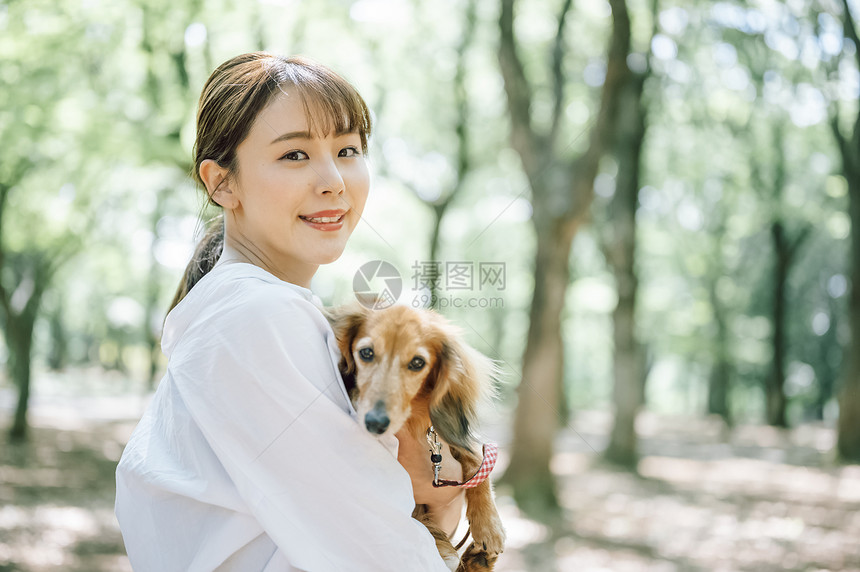 抱着宠物狗开心的年轻女子图片