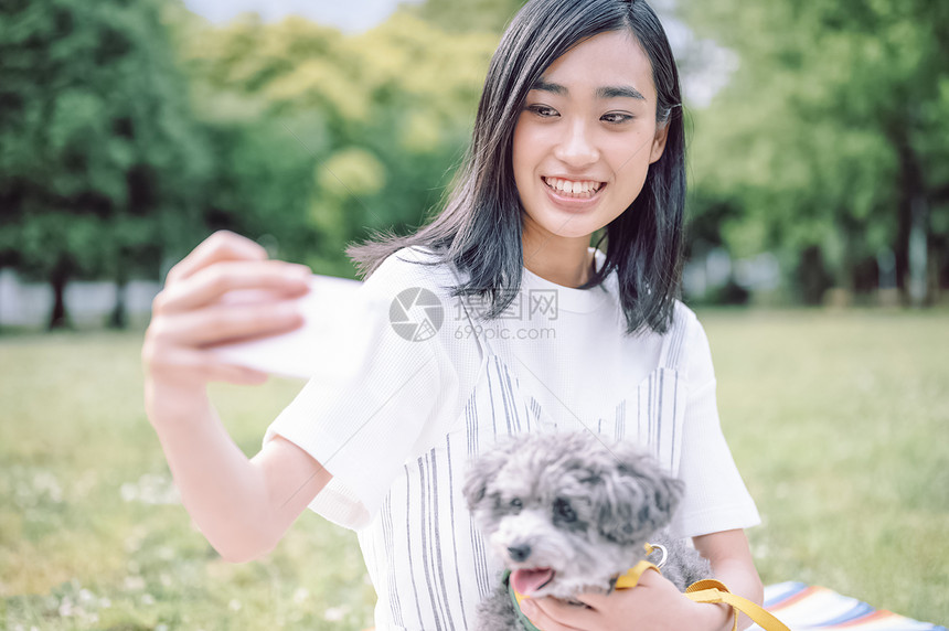 公园里抱着宠物狗自拍的女人图片