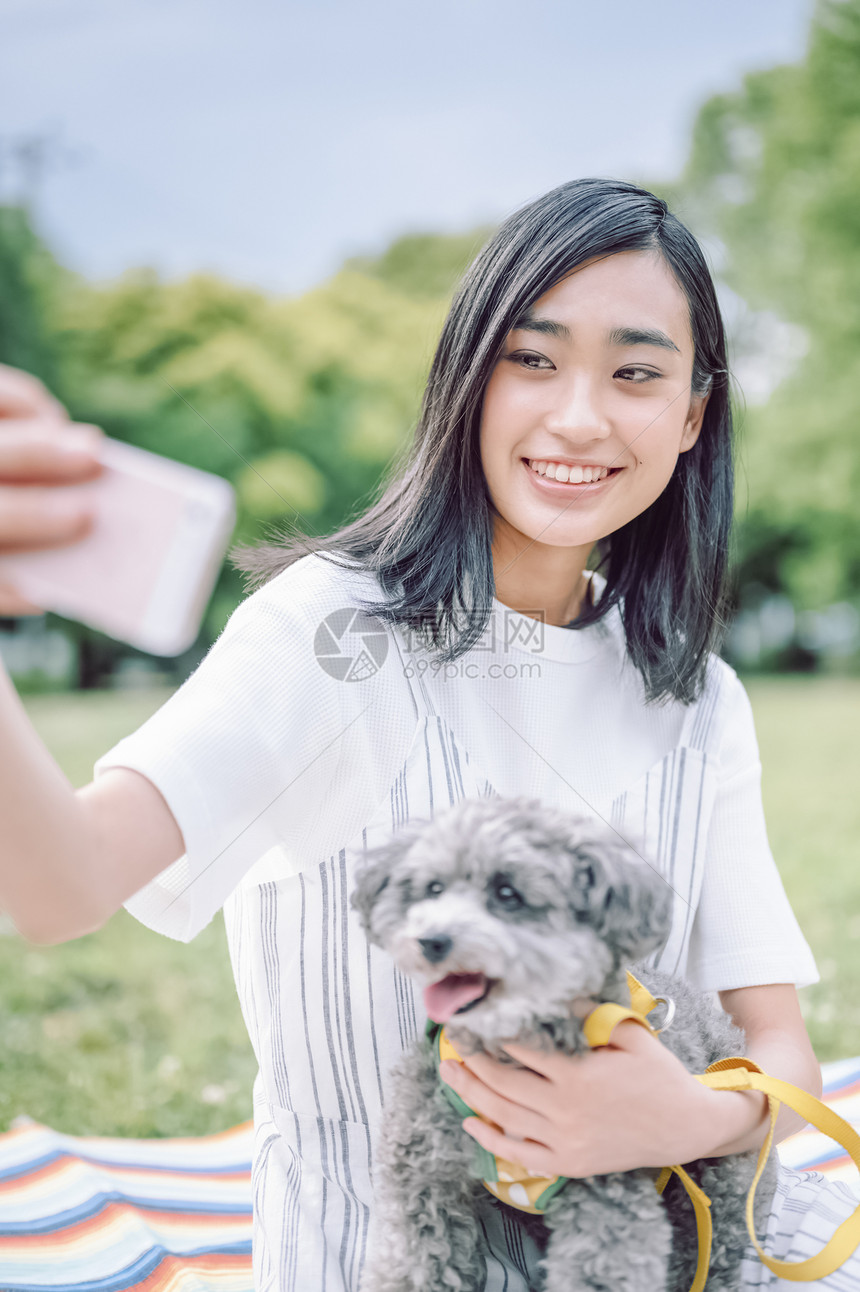 抱着宠物狗自拍的年轻女子图片