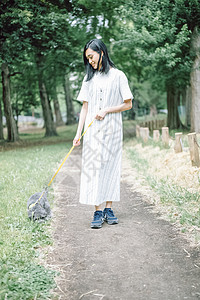 公园里遛狗的年轻女子图片