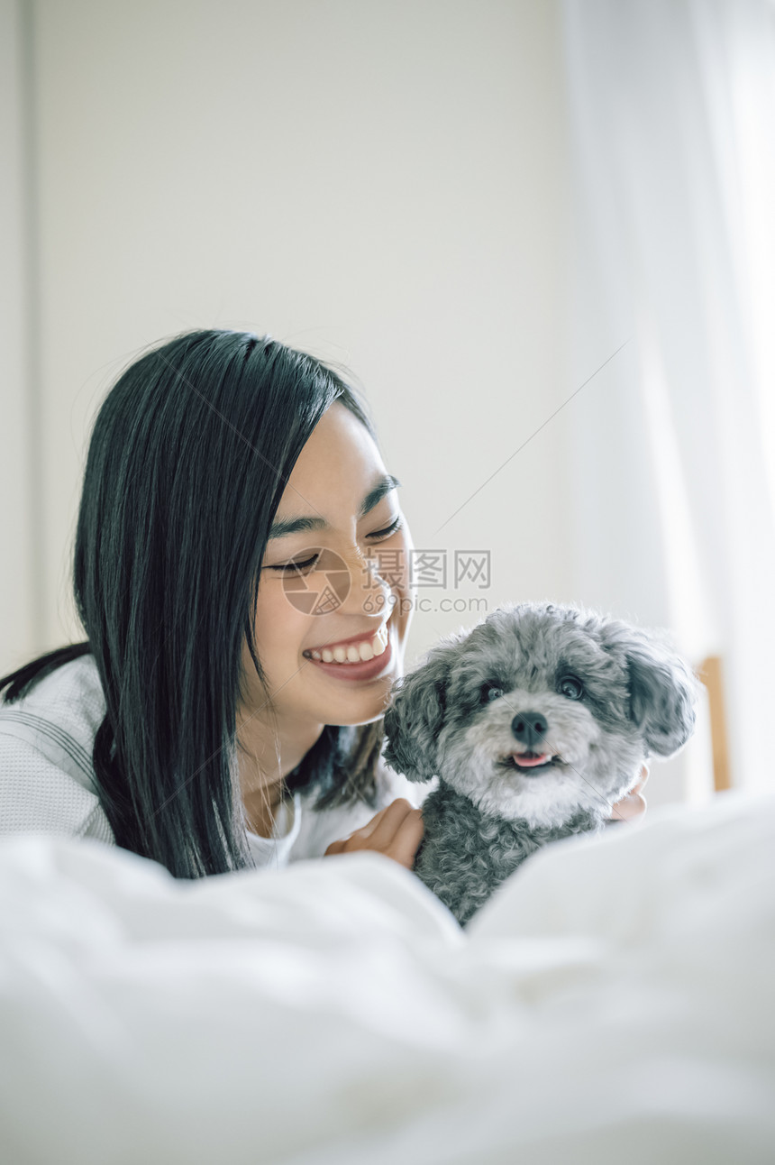 室内微笑的女人抱着宠物狗图片