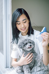 窗边抱着宠物狗的女人图片