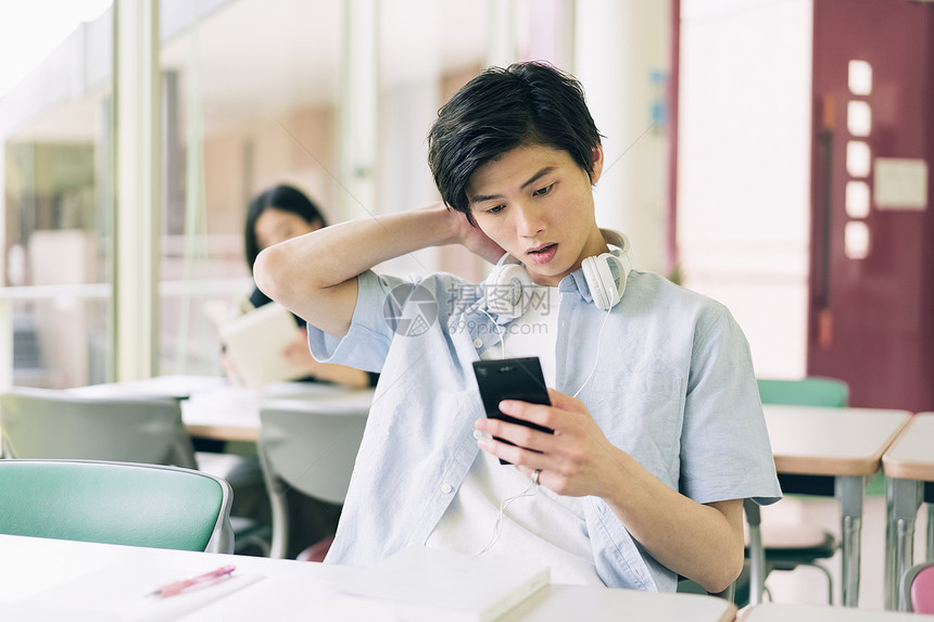 人物看文稿空间男大学生智能手机摄影合作keisenjogakuen大学图片