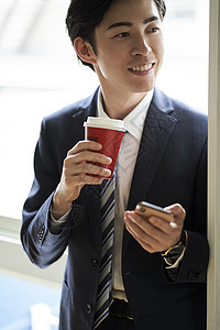 公司的男子看手机喝咖啡图片