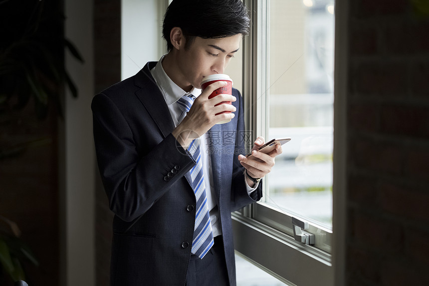 公司的男子看手机喝咖啡图片