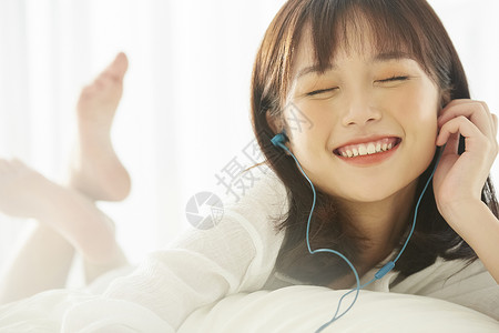 可爱女生在床上开心听音乐图片