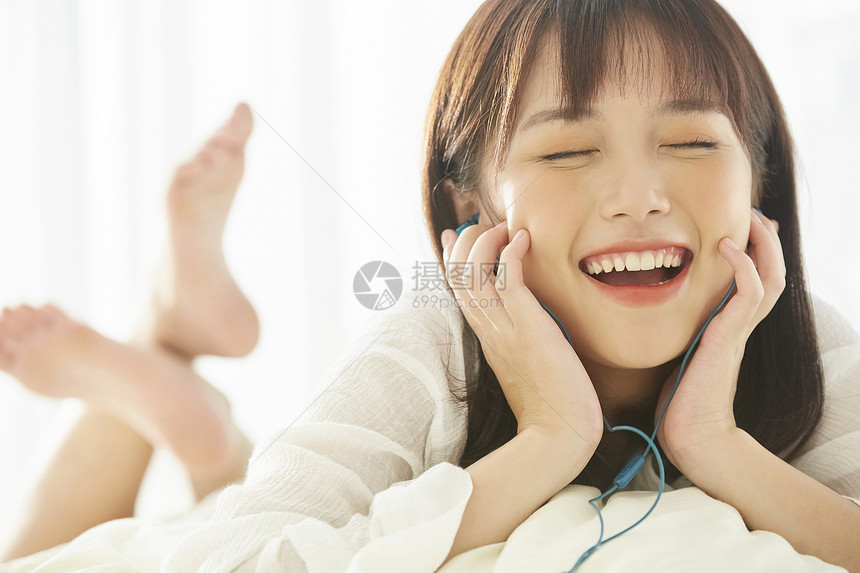 可爱女生在床上开心听音乐图片