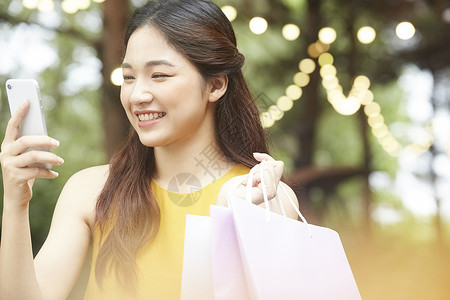 年轻女人拎着购物袋购物看手机图片