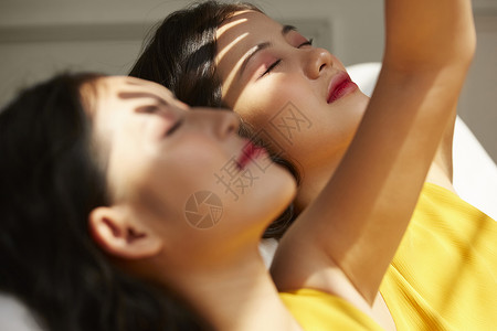 两个年轻女人躺在光影下笑容高清图片素材