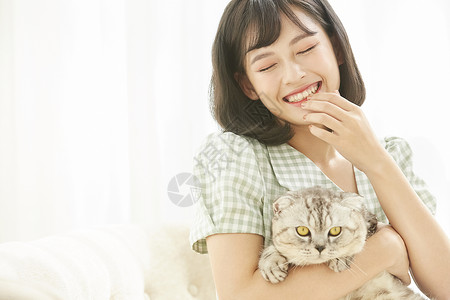 抱着宠物猫咪微笑的女青年图片