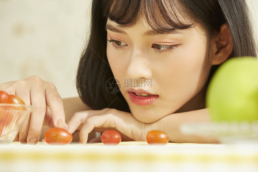 看着小番茄的年轻女子图片