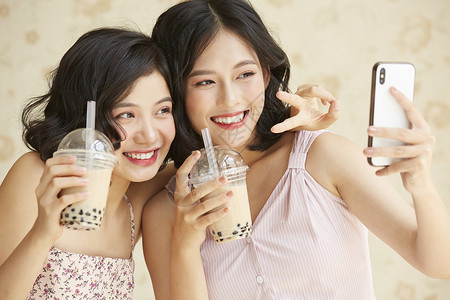 亲密姐妹开心的喝奶茶自拍咖啡店高清图片素材