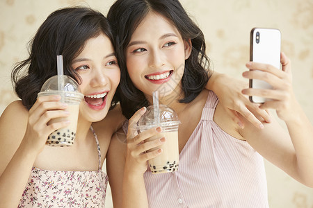 亲密姐妹开心的喝奶茶自拍图片