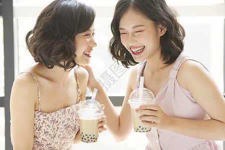 亲密姐妹开心的喝奶茶咖啡厅高清图片素材
