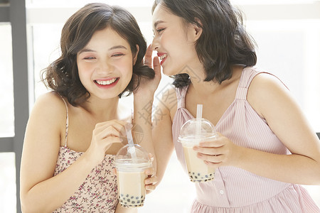 亲密姐妹开心的喝奶茶喝酒高清图片素材