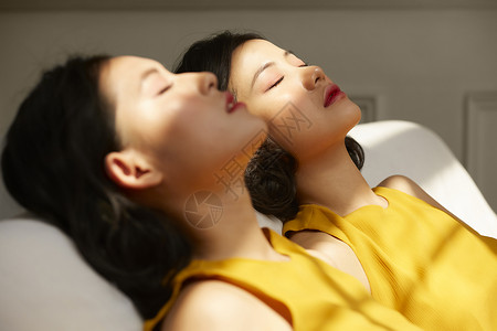两个年轻女人躺在光影下日光高清图片素材