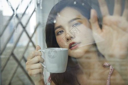 下雨天喝咖啡的青年女子图片