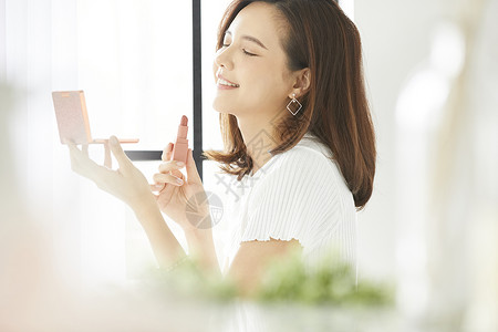 窗边化妆的年轻女人图片