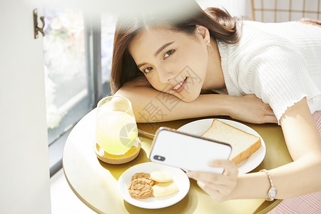 早餐拿着手机自拍的年轻女子图片