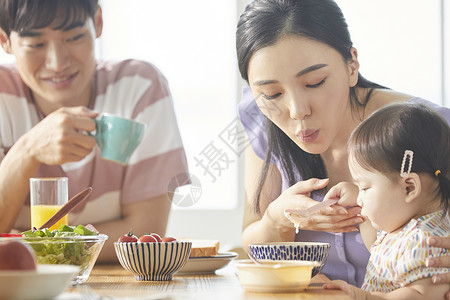 年轻一家人照顾孩子用餐图片