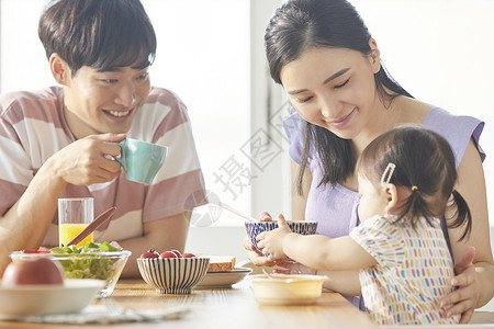 年轻一家人照顾孩子用餐图片