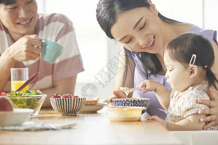 年轻一家人照顾孩子用餐高清图片