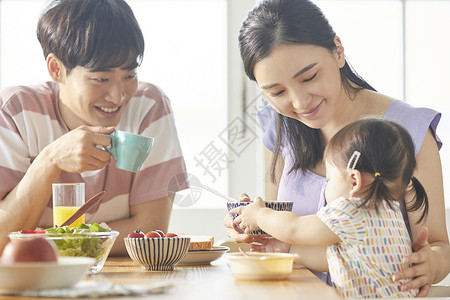 年轻一家人照顾孩子用餐图片