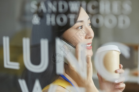 年轻女人拿着咖啡讲电话图片