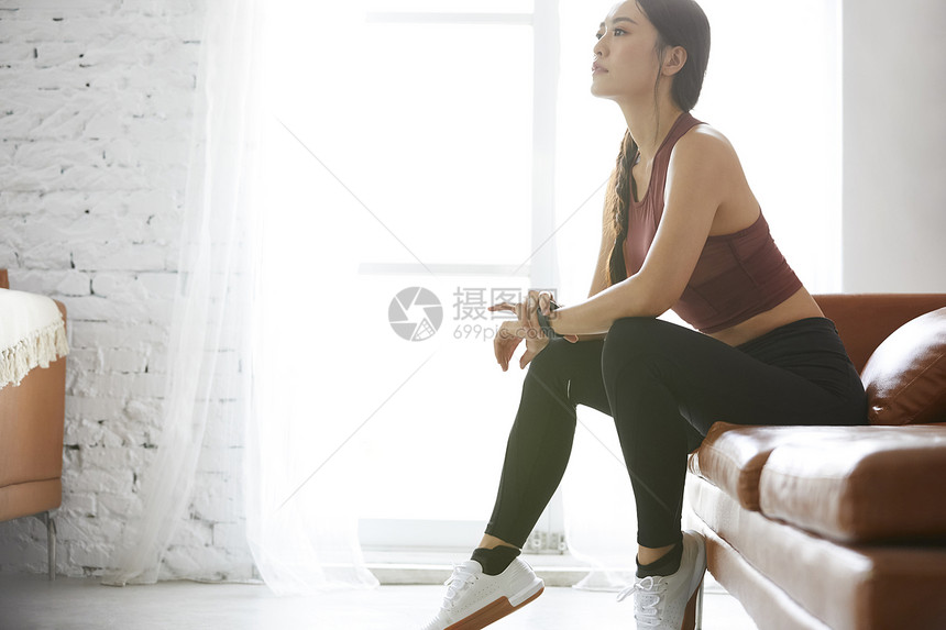 穿着运动鞋坐在沙发上的运动女性图片