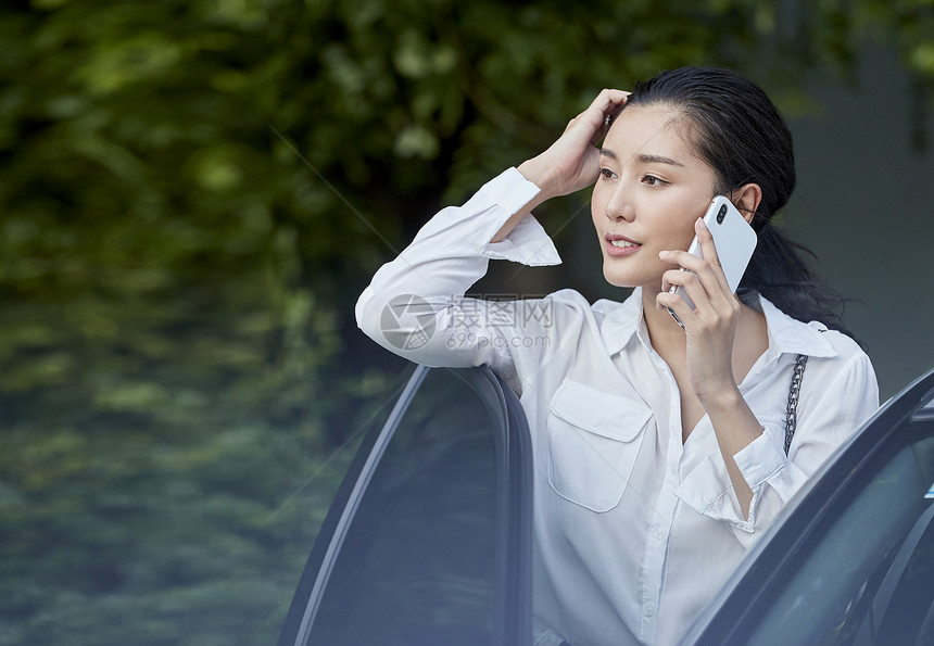 女人站在车边接打电话图片