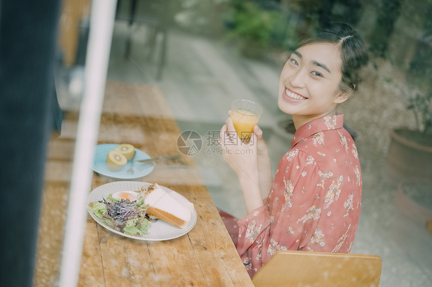 室内用餐的年轻女人看向窗外图片