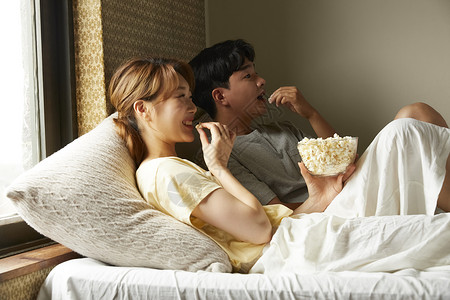 床上休息的愉快年轻夫妻吃零食图片