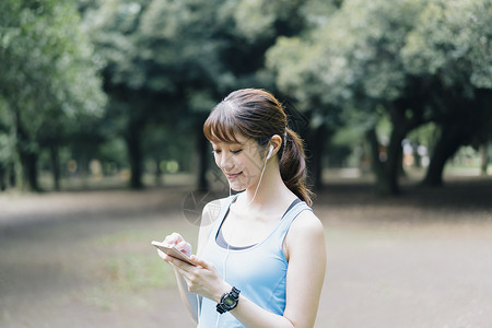 低头看着手机的运动女性图片