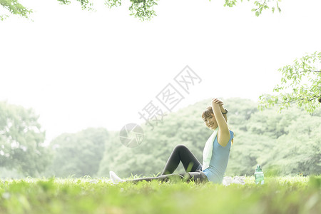 户外草坪上做瑜伽拉伸的女青年图片