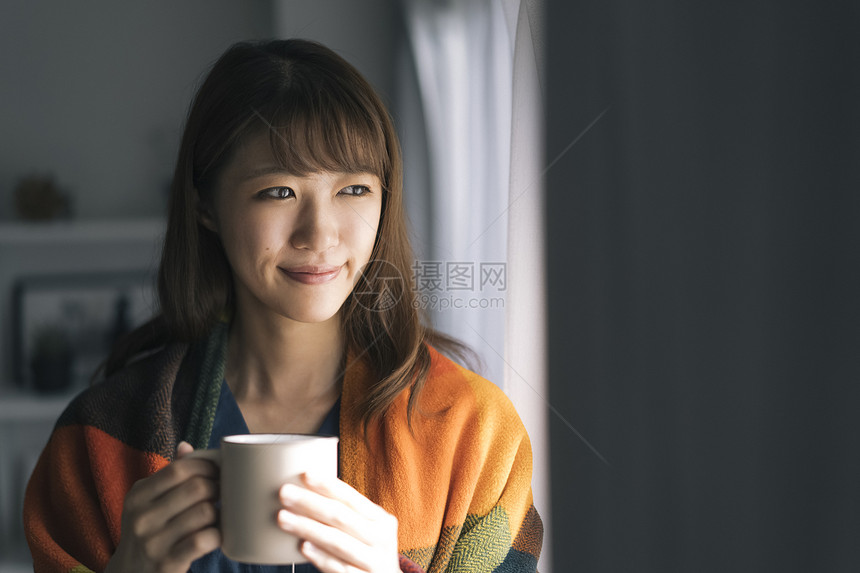 居家捧着咖啡看向窗外的女青年图片