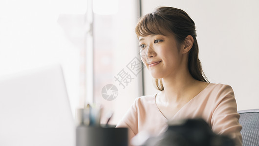 看着笔记本电脑微笑的商务女性高清图片