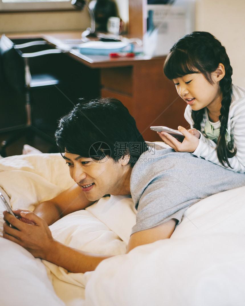 床上爸爸陪女儿玩手机图片