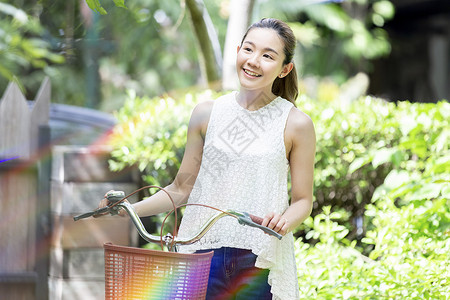 户外推着自行车微笑的年轻女子图片