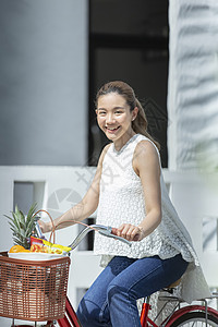 户外骑着脚踏车购物的女性图片