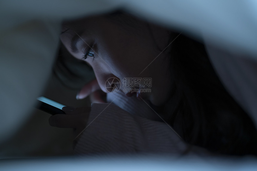 少女感的光线生活方式智能手机上床睡觉图片