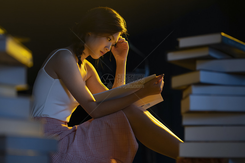 昏黄的灯光下年轻女人在看书阅读图片