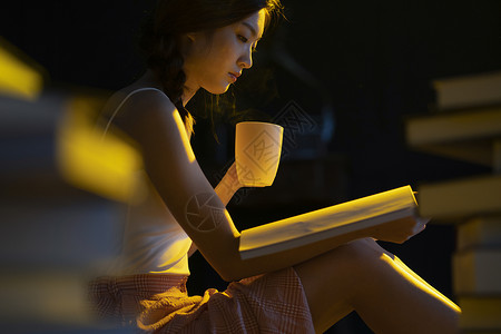 昏黄的灯光下年轻女人在看书阅读图片