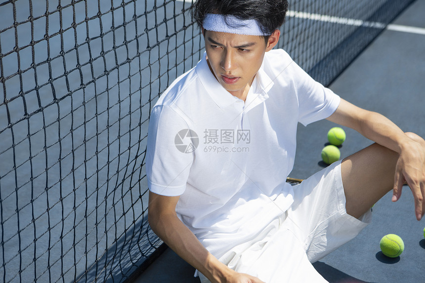 坐在网球场休息的青年男子图片