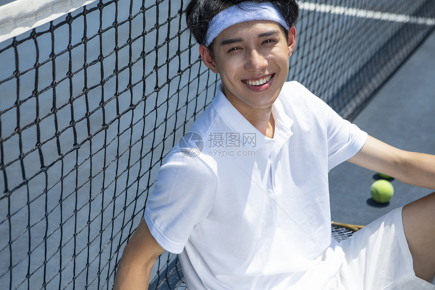 坐在网球场休息微笑的青年男子图片
