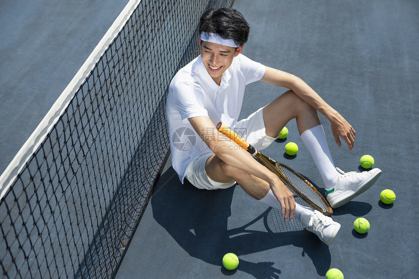 坐在网球场上休息的男青年图片