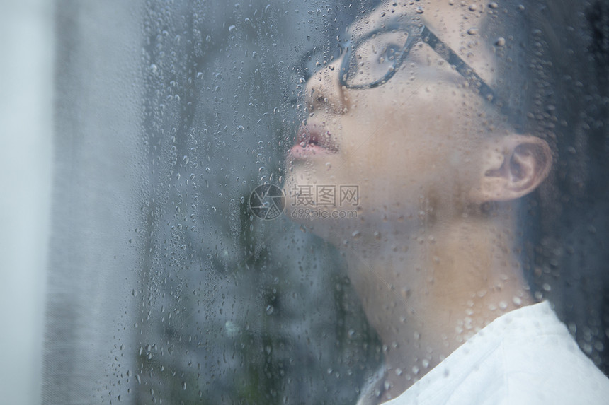 下雨天看向窗外沉思的男青年图片