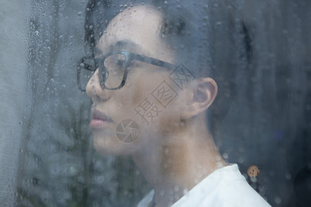 雨天看向窗外思考的青年男性图片