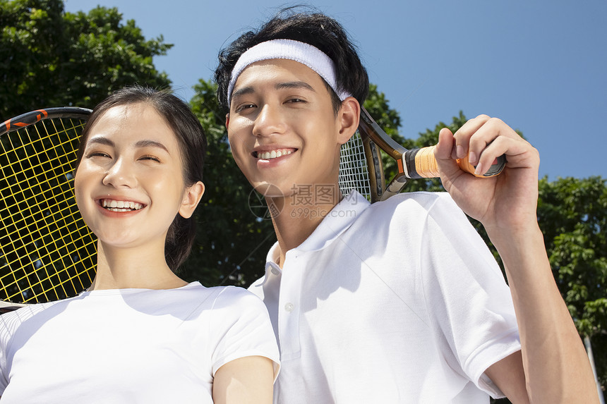 在户外网球场打网球的年轻情侣图片